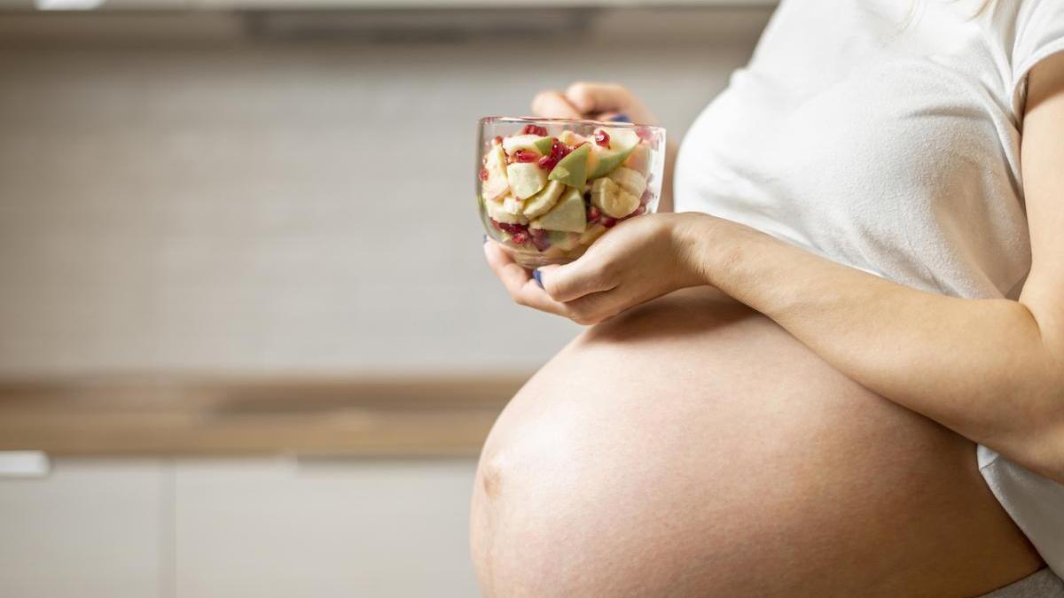 Mujer embarazada come fruta.