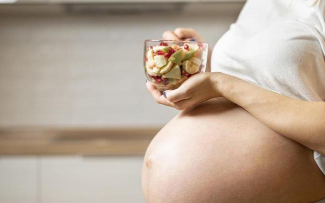 Mujer embarazada come fruta.