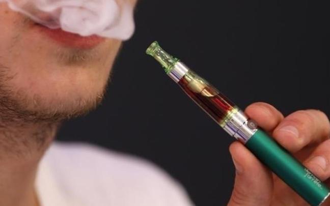 Un joven vapea con un cigarrillo electrónico.