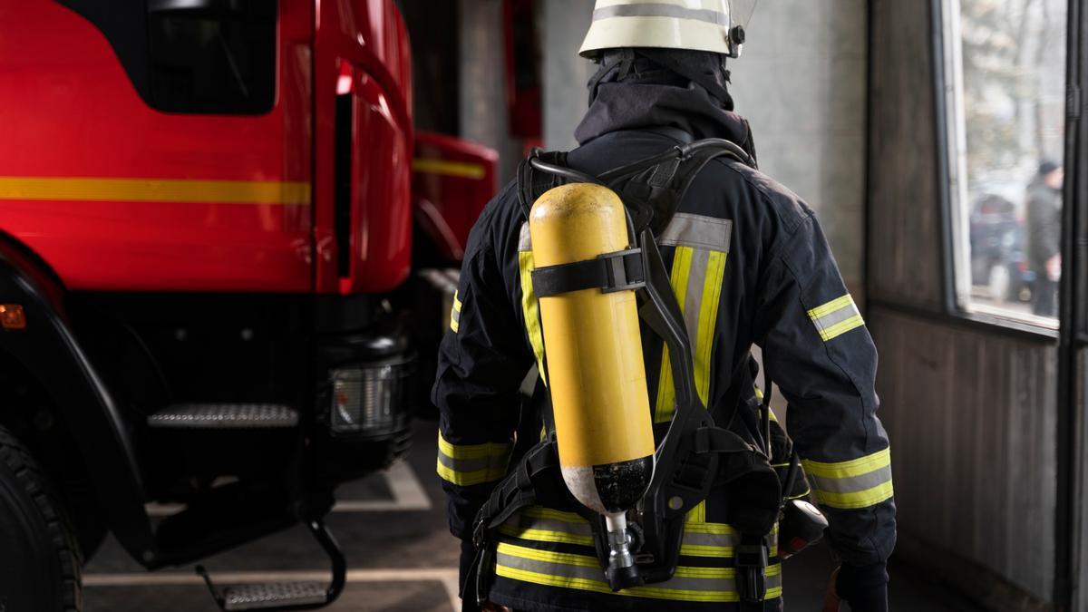 Un bombero preparado junto a un camión.
