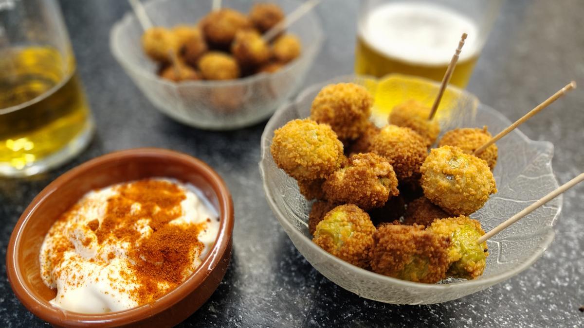 Un par de raciones de aceitunas fritas listas para disfrutar con un cuenco de salsa.