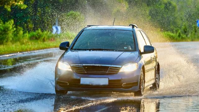Un coche atraviesa una balsa de agua en la carretera.