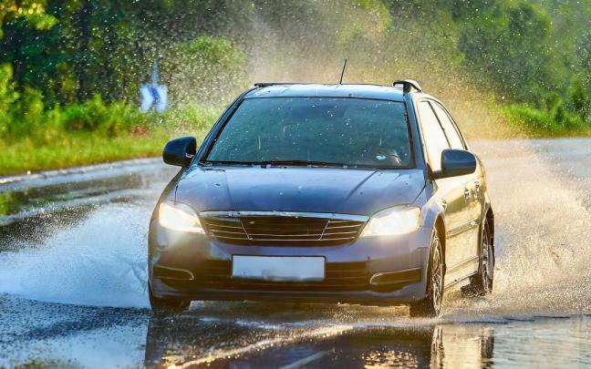 Un coche atraviesa una balsa de agua en la carretera.
