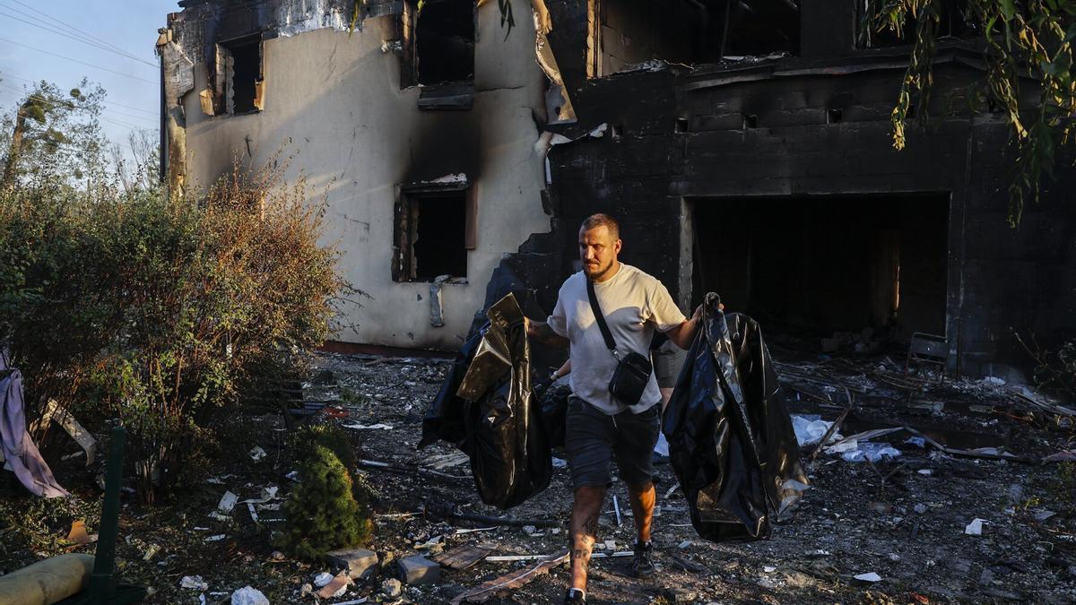 Un miembro de un equipo especial transporta bolsas de plástico que contienen los restos de las víctimas en el lugar de un ataque con drones rusos en el patio de una residencia de ancianos en la aldea de Myla, cerca de Kiev, Ucrania, el 29 de agosto de 2026.