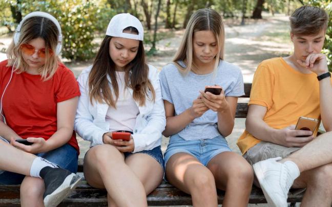 Un grupo de amigos cada uno pendiente de su móvil.