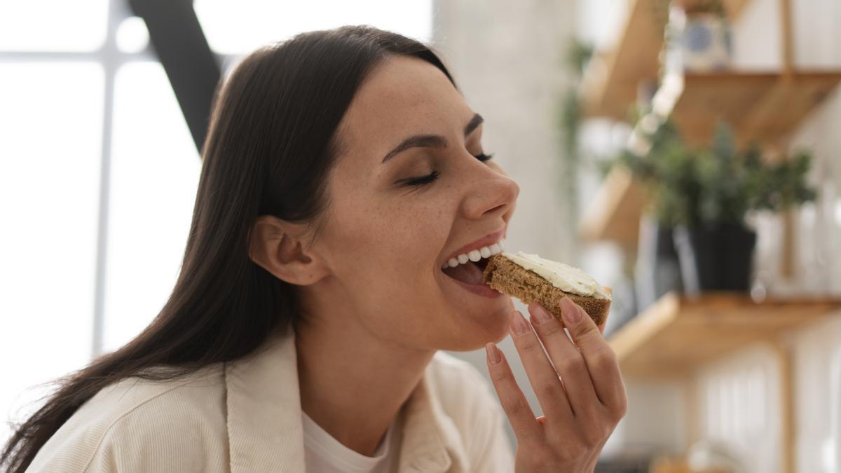 Chica come una rebanada de pan con queso fresco para picar entre horas.