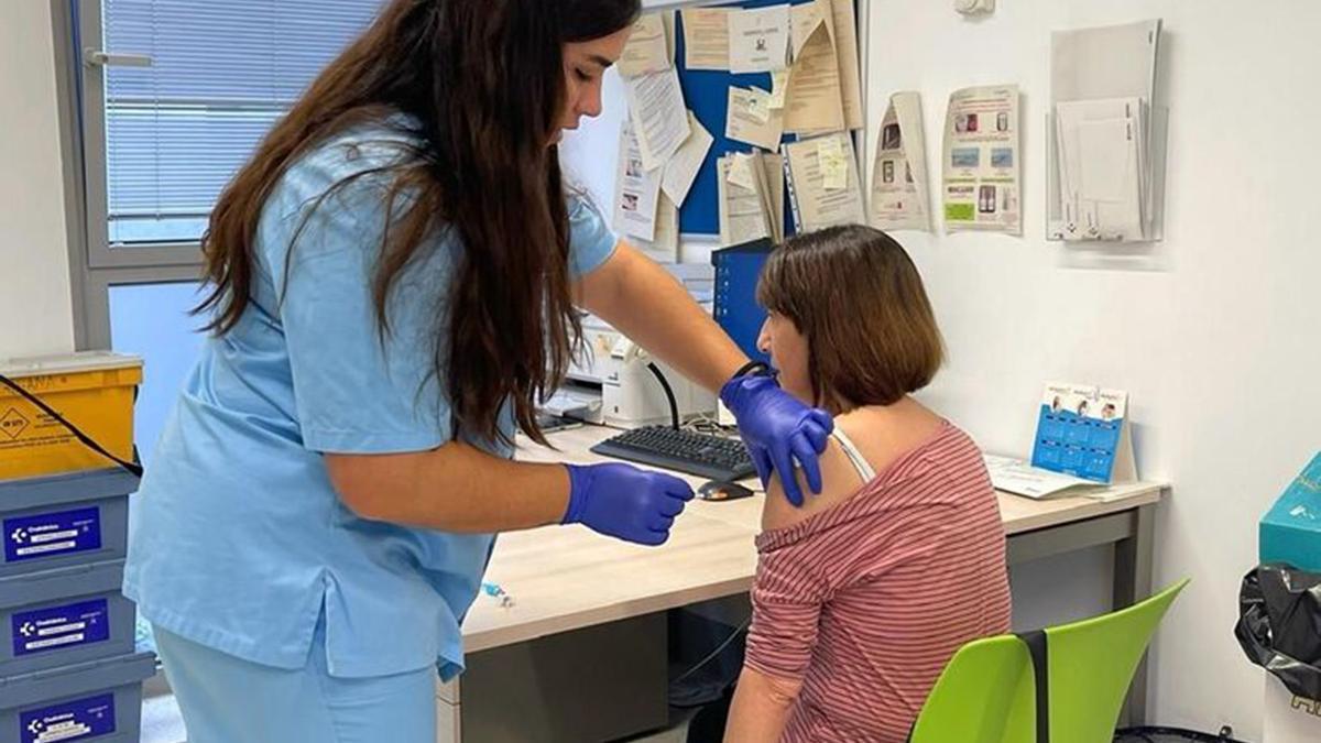 Una sanitaria vacuna a una mujer en un centro sanitario.