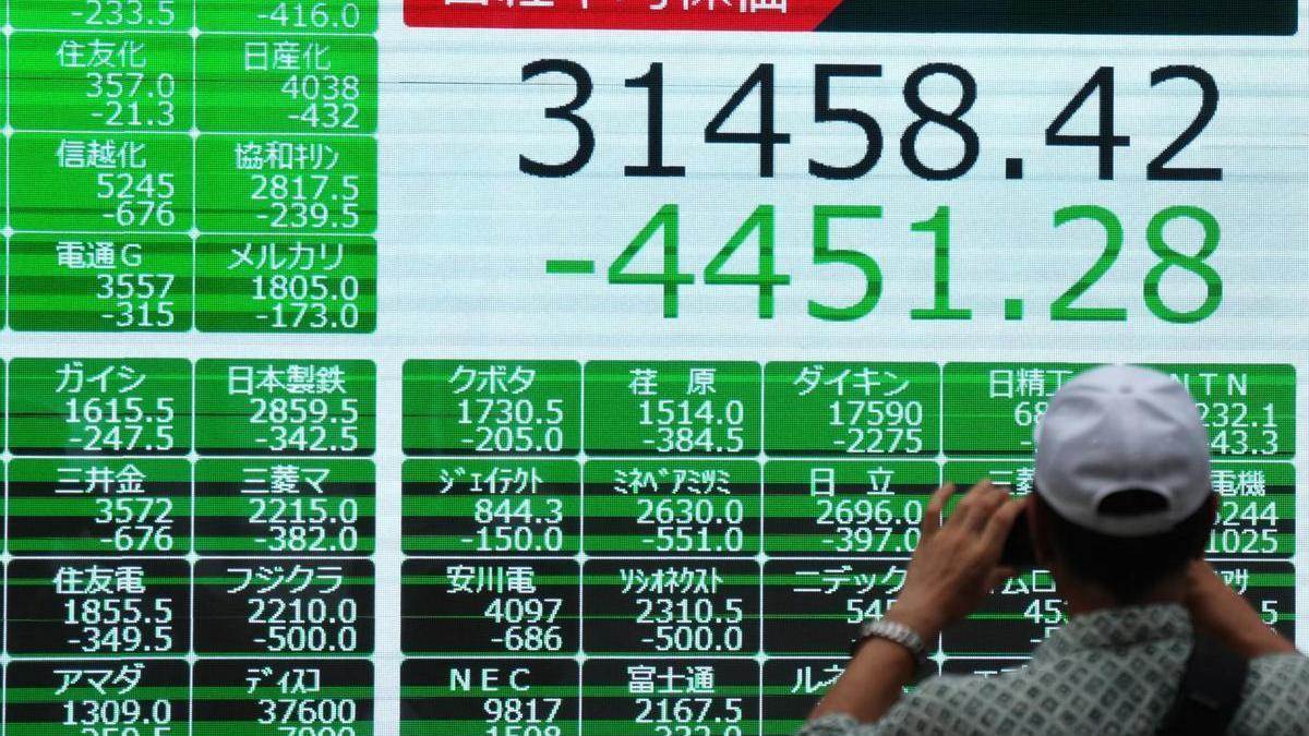 Un hombre saca una foto a los datos de cierre del Nikkei.