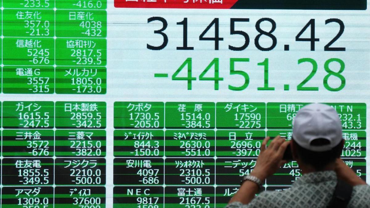 Un hombre saca una foto a los datos de cierre del Nikkei.