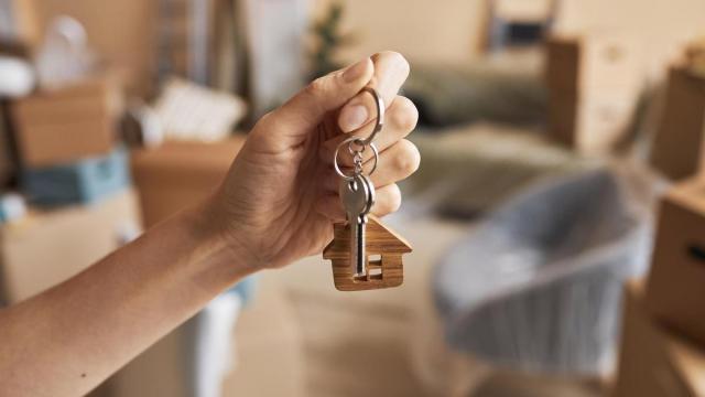 Una mujer sostiene en su mano las llaves de su nueva vivienda.