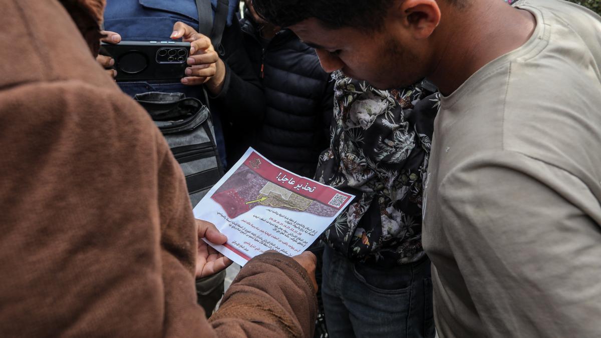 Varios gazatíes leen un cartel donde se insta a evacuar la ciudad de Rafáh.