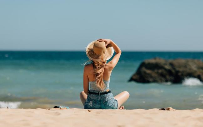 Una mujer se relaja sentada mirando al mar. Una mujer se relaja sentada mirando al mar.