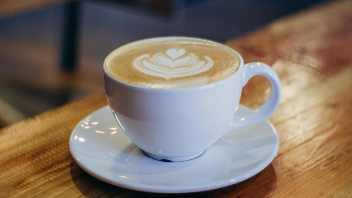 Una taza de café con el dibujo de una flor en la espuma.