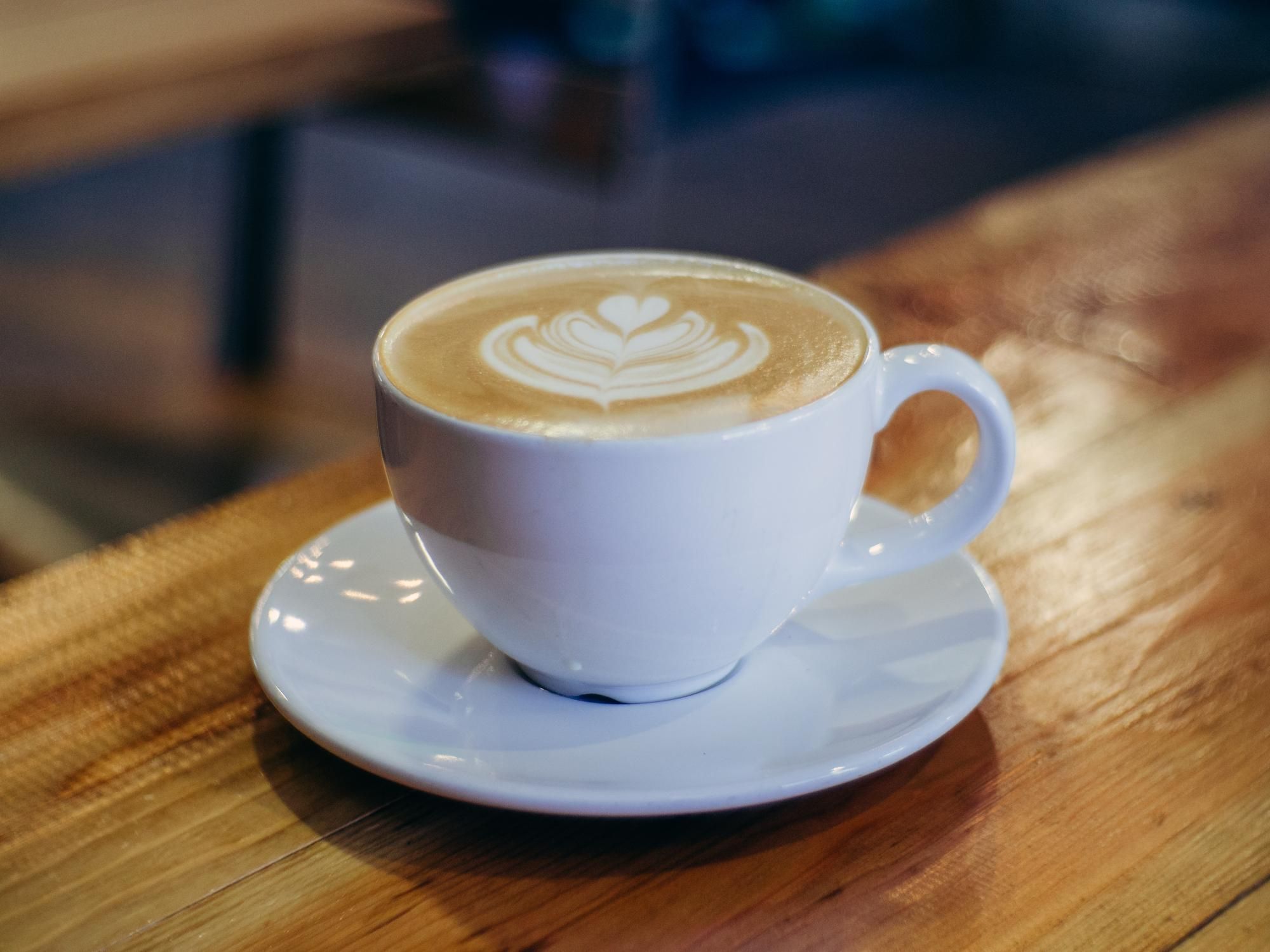 Una taza de café con el dibujo de una flor en la espuma.