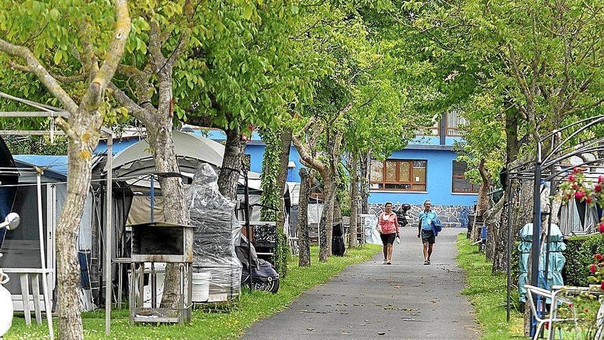 Dos personas caminando entre las parcelas de un camping.