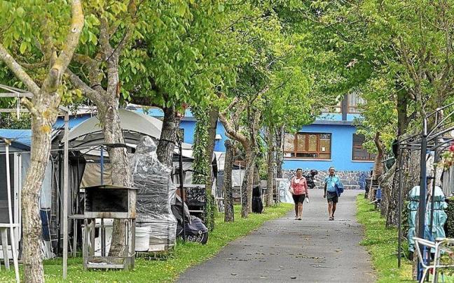 Dos personas caminando entre las parcelas de un camping.