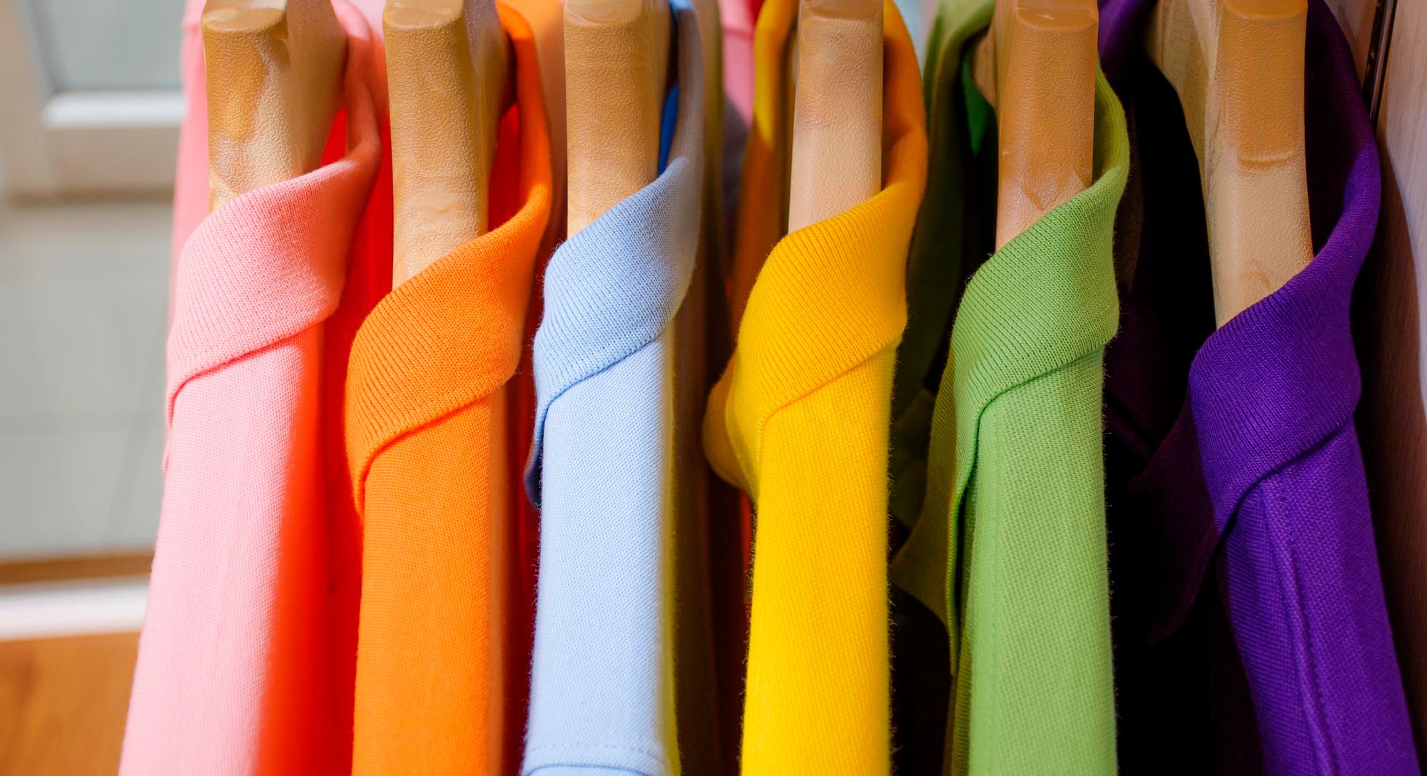 Polos de distintos colores colgados en perchas.