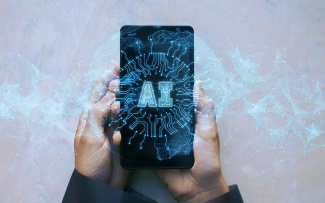 Un usuario sujeta un móvil con un holograma de inteligencia artificial.