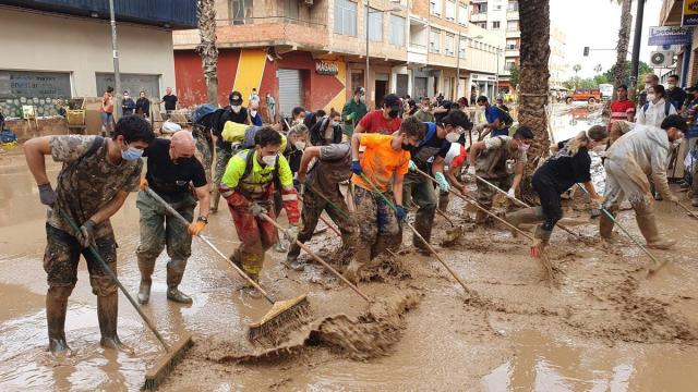 Voluntarios y vecinos de Paiporta achican el agua concentrada en las calles.