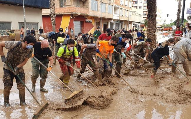 Voluntarios y vecinos de Paiporta achican el agua concentrada en las calles.