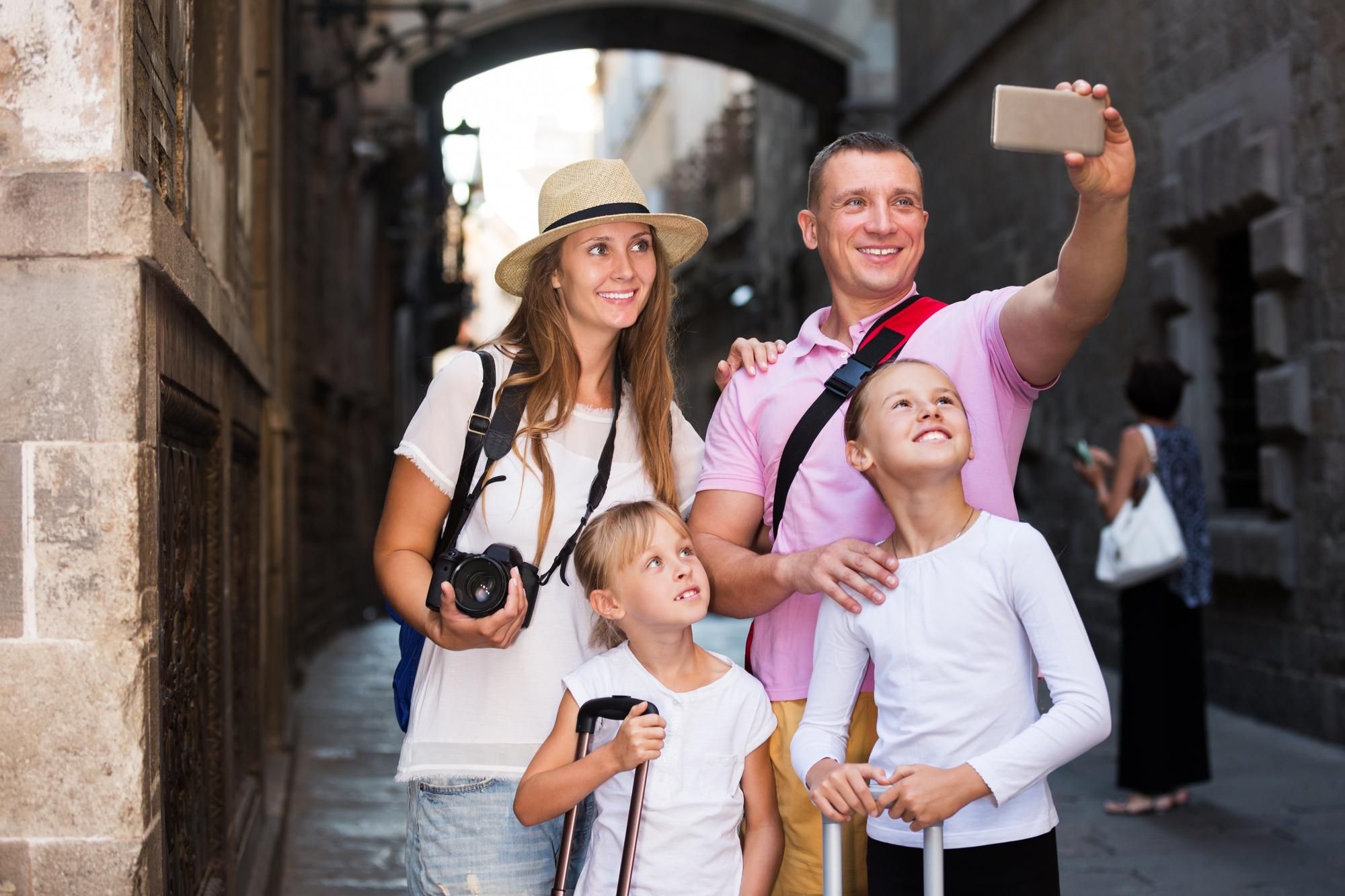 Una familia se hace un selfie mientras visita el casco antiguo de una ciudad.