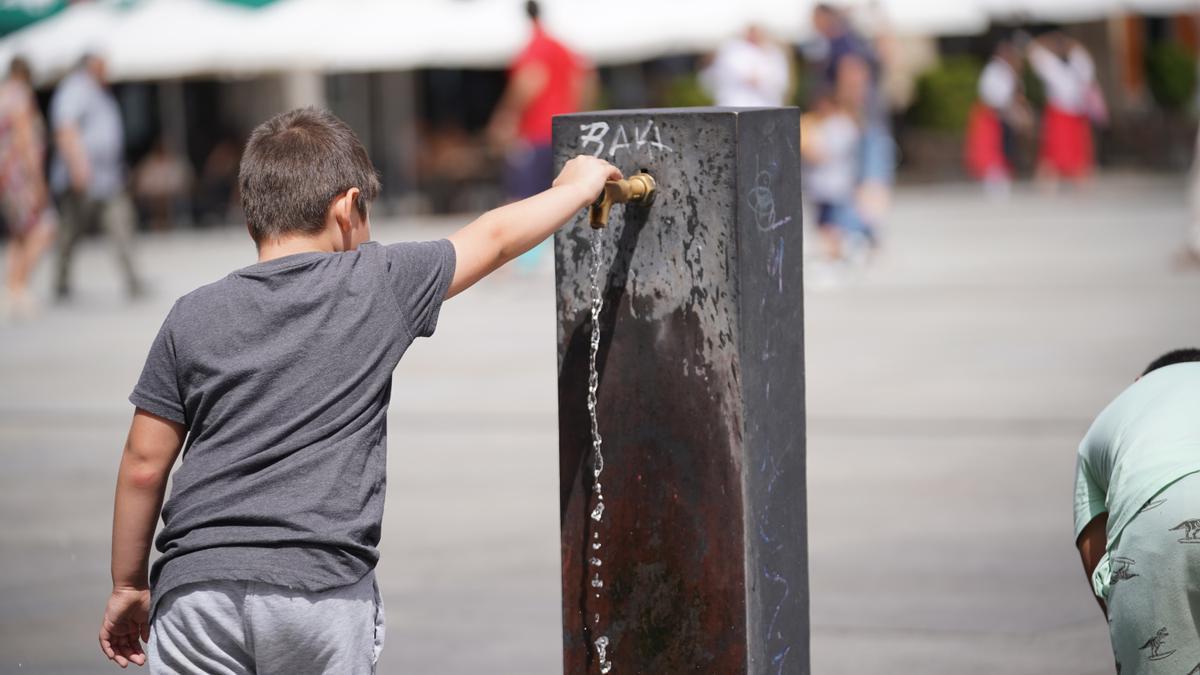 Un niño usa una fuente para refrescarse.