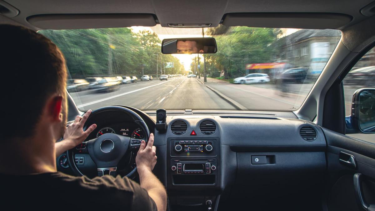 Un hombre, conduciendo su coche por la ciudad.