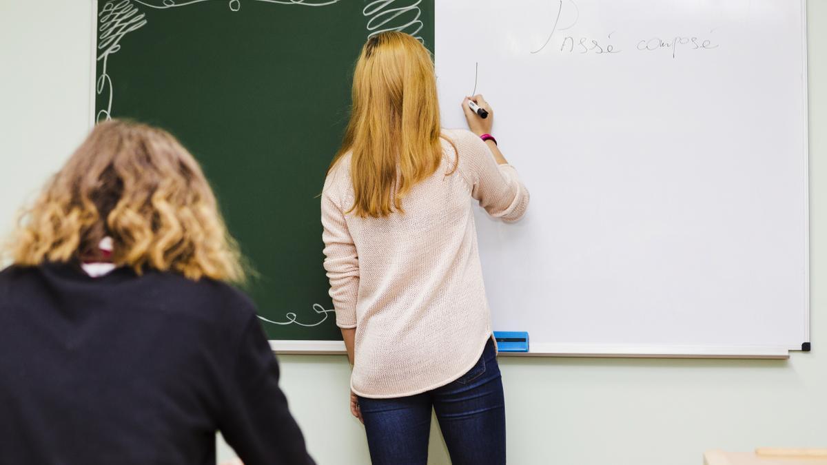 Imagen de una profesora escribiendo en una pizarra