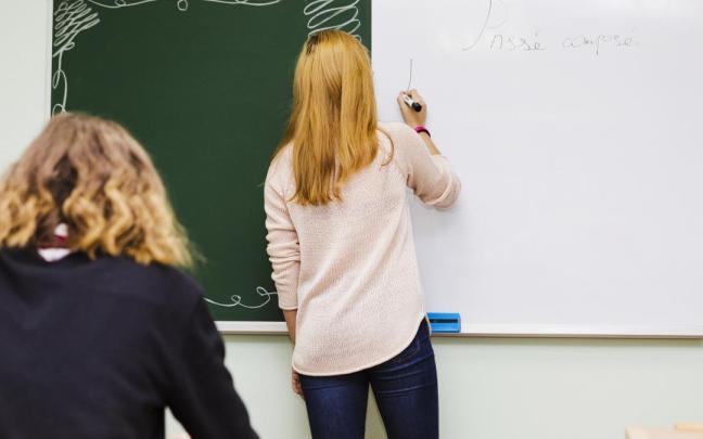 Imagen de una profesora escribiendo en una pizarra
