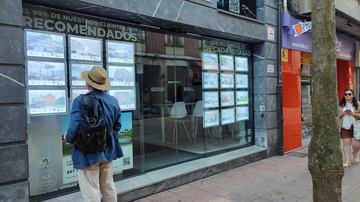 Un hombre mira anuncios de una agencia inmobiliaria, con viviendas de segunda mano a la venta.