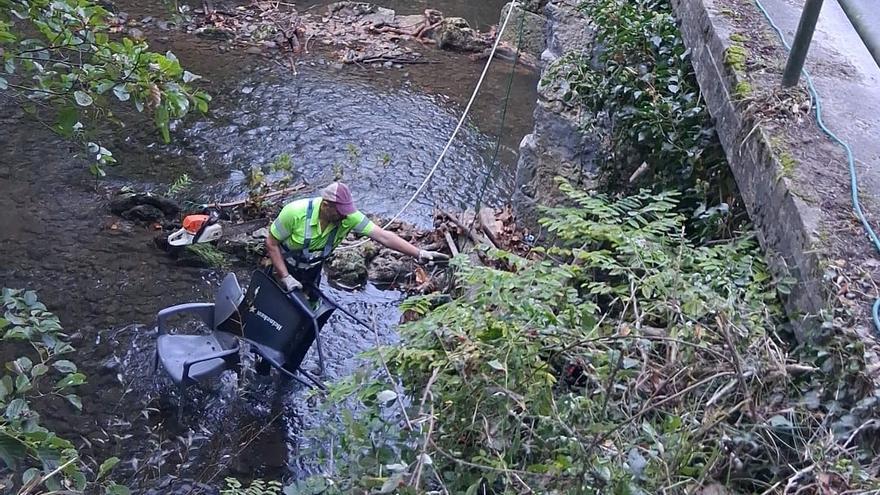 Operario retirando sillas de plástico del cauce de uno de los ríos de Lemoa