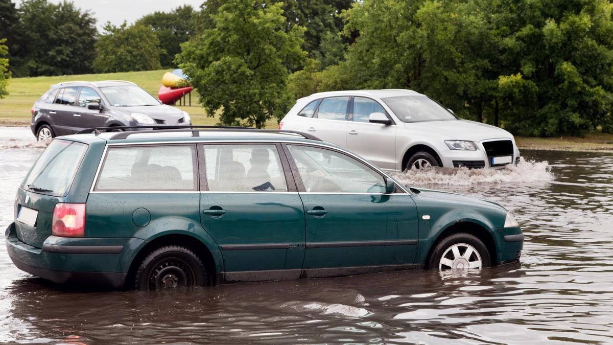 Varios coches circulan por una carretera inundada.