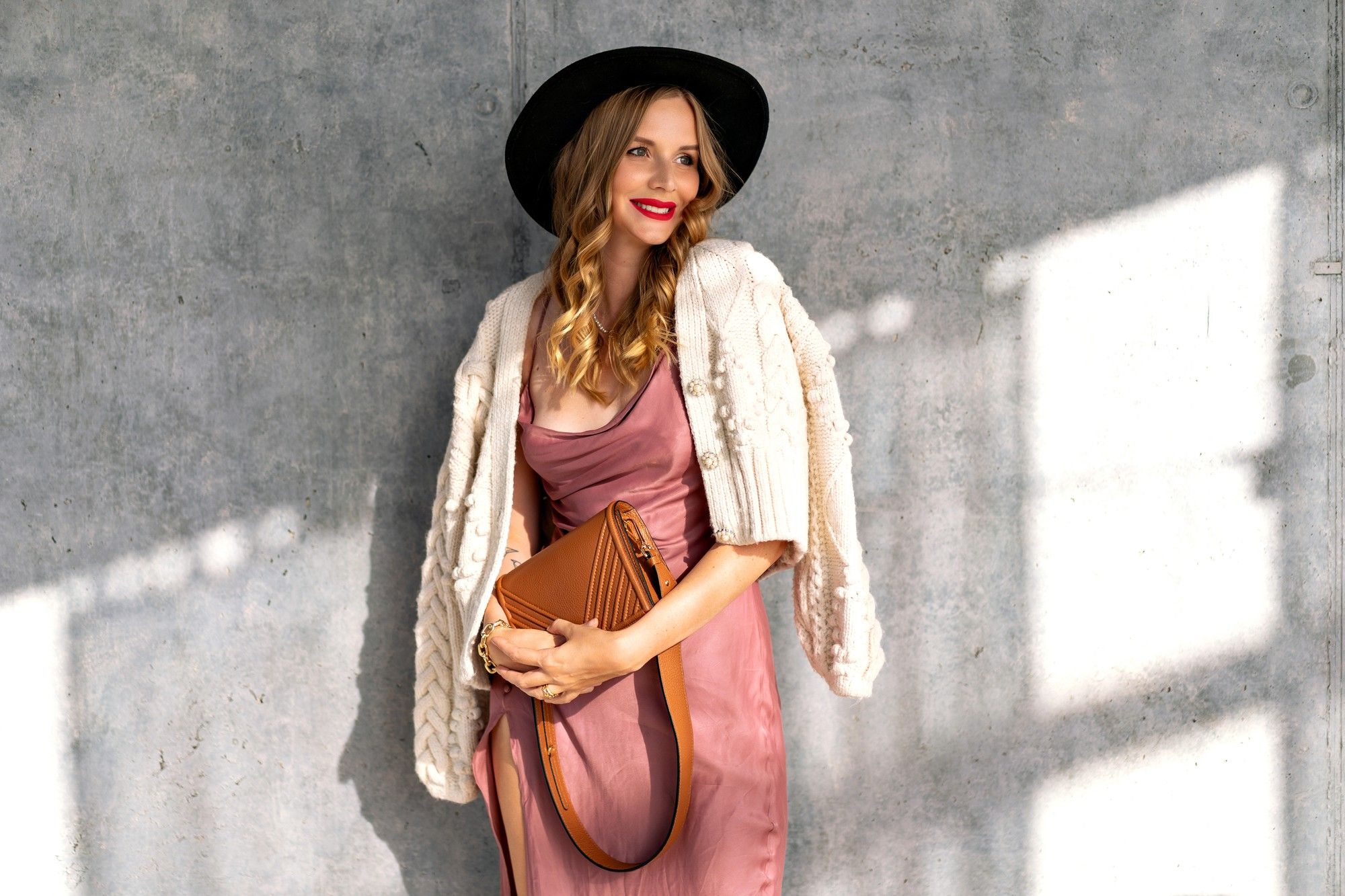 Vestido rosa con chaqueta beige de punto.