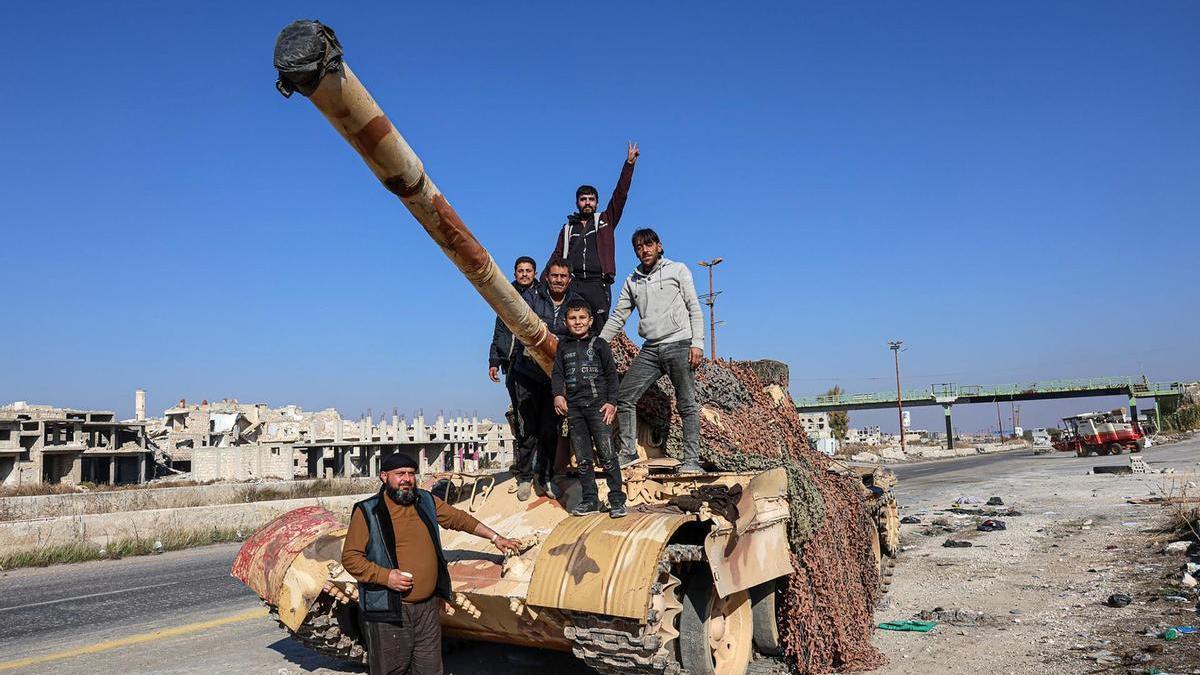 Ciudadanos subidos a un tanque capturado por la oposición siria en la autopista que une Alepo y Damasco.