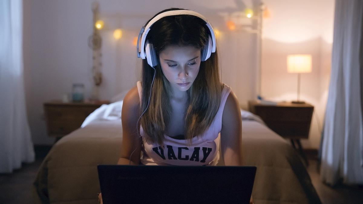 Joven utilizando el ordenador en su habitación.