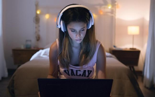 Joven utilizando el ordenador en su habitación.