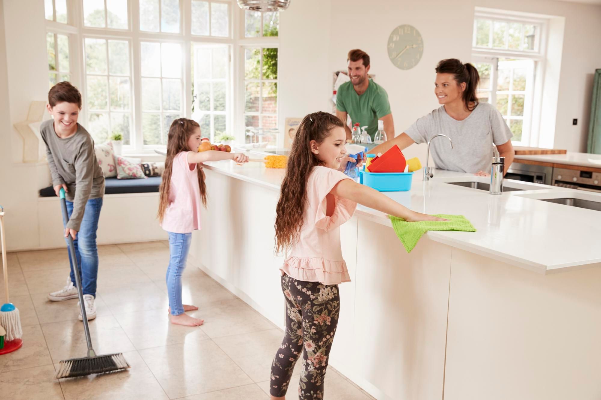 Padres e hijos limpian a fondo la cocina de su casa.