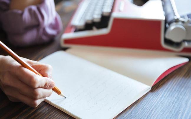 Una mujer escribe en un cuaderno. Una mujer escribe en un cuaderno.