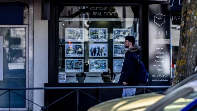 Un joven mira el escaparate de una inmobiliaria.