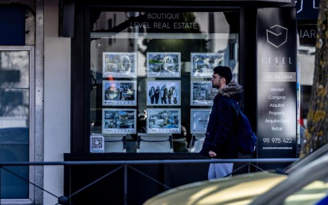 Un joven mira el escaparate de una inmobiliaria.