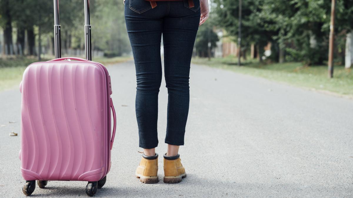 Una joven posa con su maleta antes de realizar un viaje.