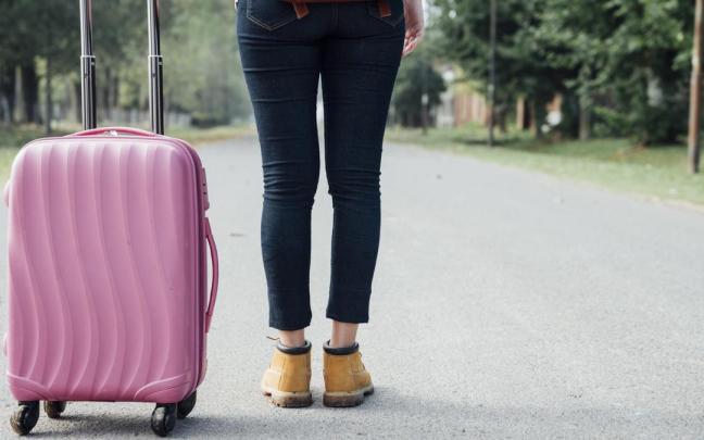 Una joven posa con su maleta antes de realizar un viaje.