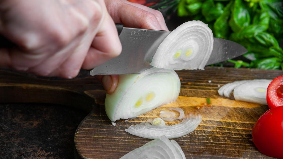 Cortar cebolla sobre una tabla de madera.