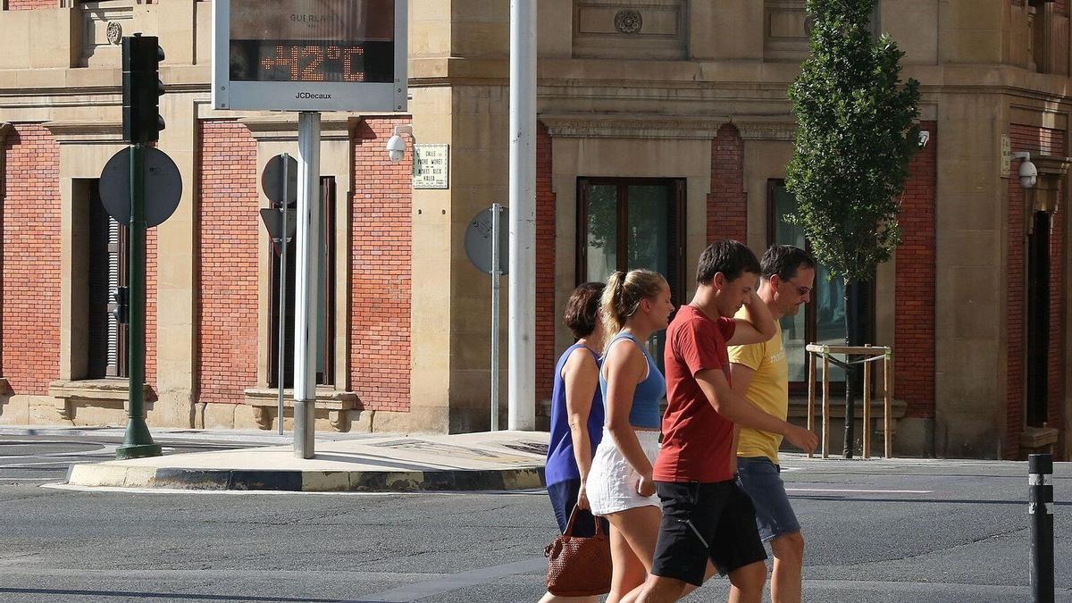 Una familia pasea por el centro de Pamplona con el termómetro al fondo marcando 42ºC.