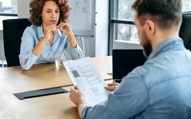 Un responsable de RRHH lee el curriculum de una candidata.