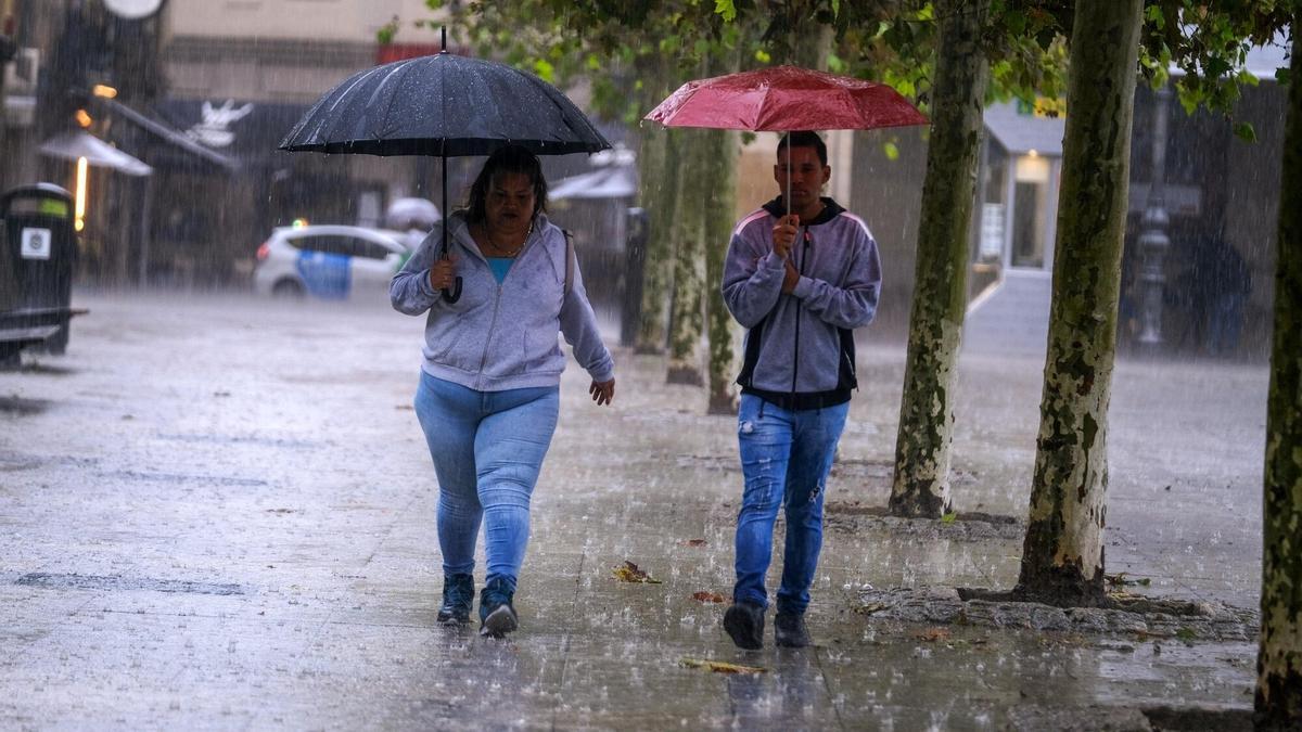 Dos personas se protegen de la lluvia en Pamplona.