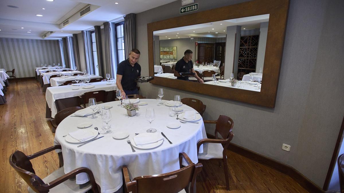 Un empleado de restauración prepara una mesa para los comensales.