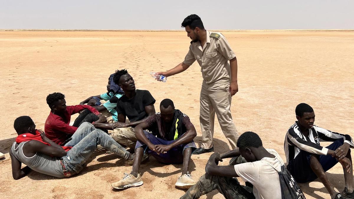 Un agente de la guardia fronteriza de Libia ofreciendo agua a los migrantes en la frontera con Túnez.