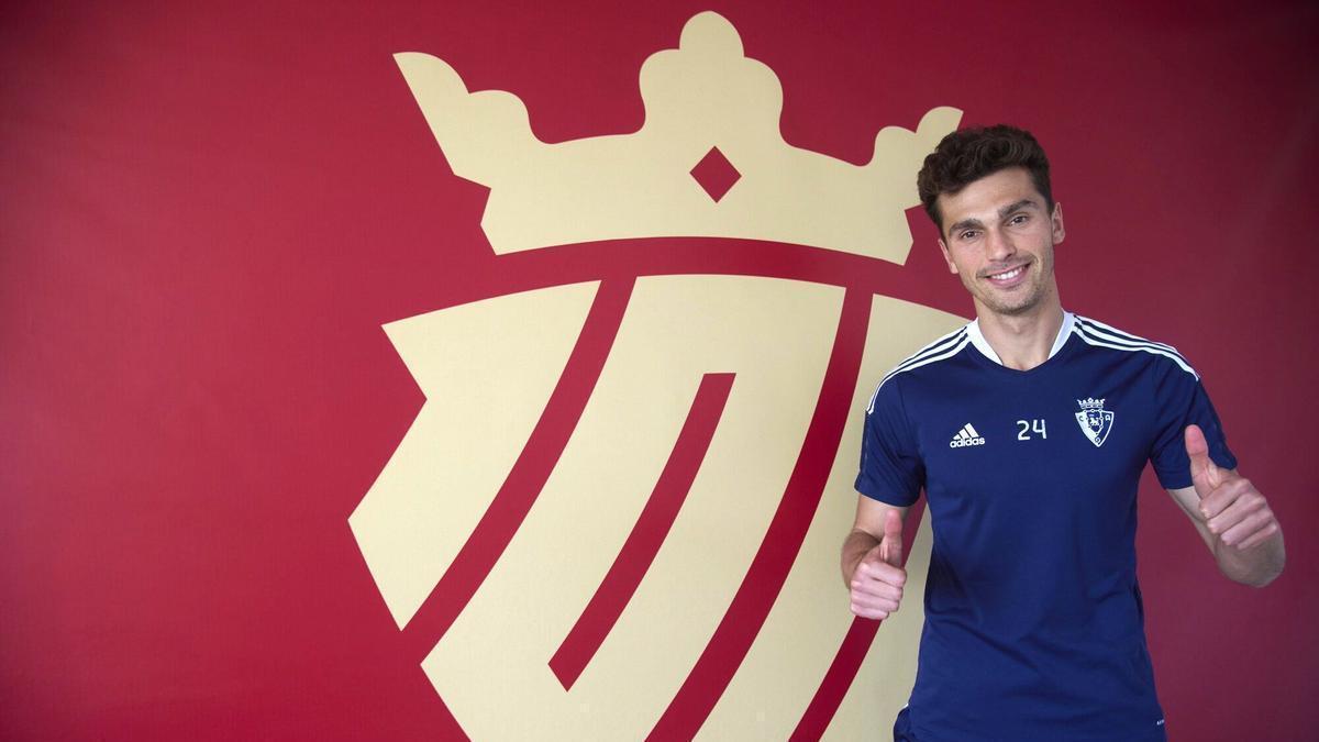 Lucas Torró posa junto al escudo del centenario de Osasuna que preside la sala de usos múltiples de las instalaciones de Tajonar.