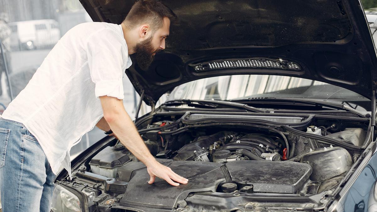 Un hombre revisa el motor de su coche.